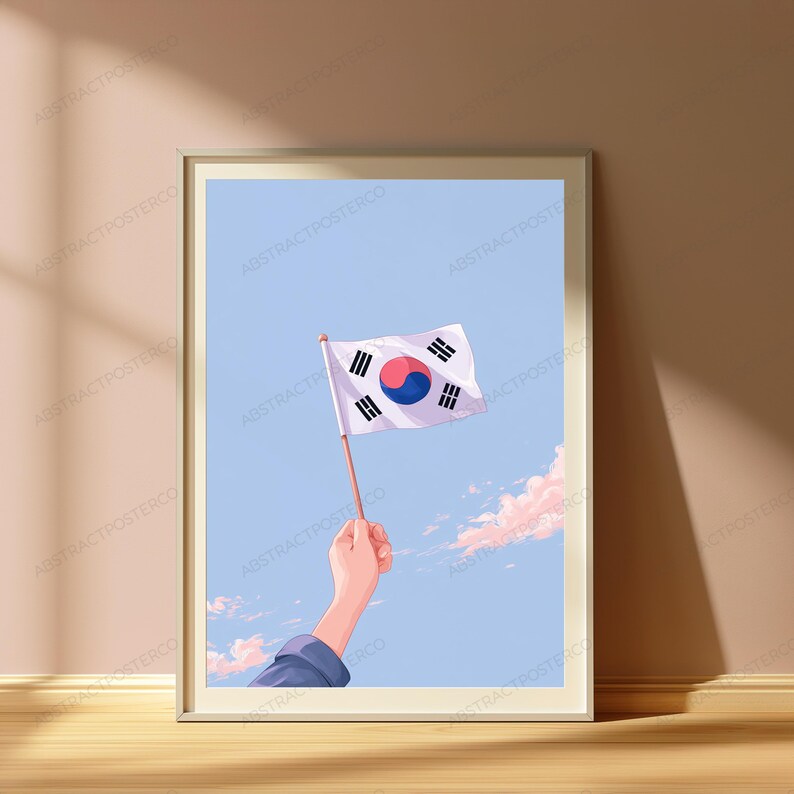 May include: A framed art print featuring an illustration of a hand holding a South Korean flag against a light blue sky with soft pink clouds. The flag displays a white background with a central red and blue taegeuk and four black trigrams.