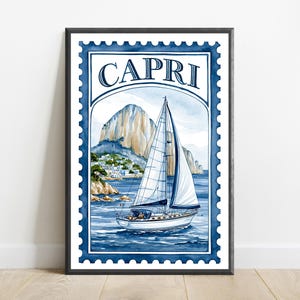 May include: A framed wall art print designed like a postage stamp featuring a watercolor illustration of a sailboat on blue water with a rocky cliffside and white buildings in the background. The word CAPRI is printed in dark blue at the top.