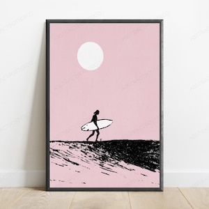 May include: A framed wall art print featuring a black silhouette of a person carrying a surfboard across a textured black landscape against a solid light pink background with a large white circle representing the sun positioned in the upper center.