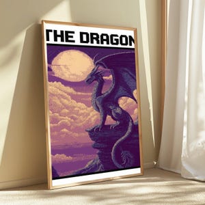 May include: A framed vertical poster featuring pixel art of a dark purple dragon perched on a rocky cliff against a backdrop of a large pale moon and purple clouds. The text THE DRAGON is printed in a bold black pixelated font at the top.