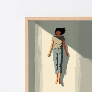 May include: A framed digital illustration featuring a person with dark hair wearing a beige t-shirt and grey cropped trousers, positioned in a vertical orientation. The figure is depicted against a background of light and shadow, enclosed in a light wood frame.