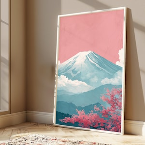 May include: A framed art print featuring a stylized depiction of Mount Fuji. The artwork showcases the mountain with a snow-capped peak, set against a pink sky and blue mountain ranges. Pink cherry blossoms are in the foreground.