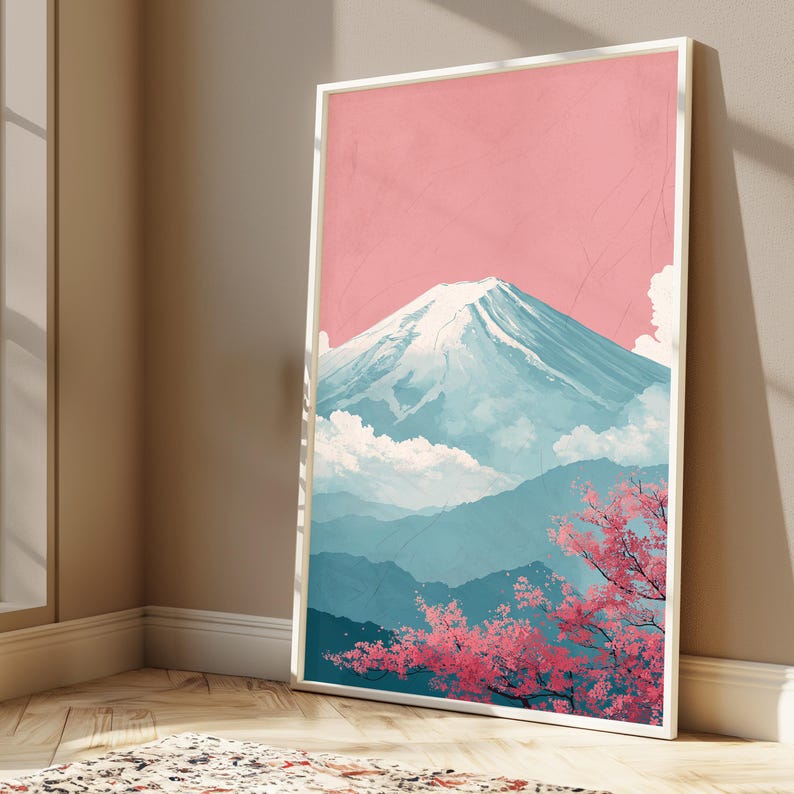 May include: A framed art print featuring a stylized depiction of Mount Fuji. The artwork showcases the mountain with a snow-capped peak, set against a pink sky and blue mountain ranges. Pink cherry blossoms are in the foreground.