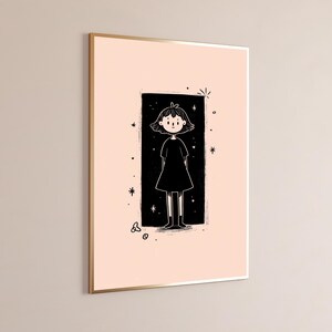 May include: A framed wall art print featuring a black and white line drawing of a person with short hair wearing a dress, centred within a black rectangular block on a pale pink background, surrounded by small star and circle graphic accents.