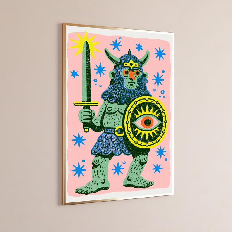 May include: A framed wall art print featuring a horned, blue-skinned warrior figure on a pink background. The figure holds a dark green sword and a round shield with a central eye motif. The scene is decorated with bright blue stars and a yellow sun.