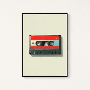 May include: A framed wall art print featuring a centered cassette tape with a red top section, a light blue middle band, and a dark gray bottom housing. The number 62 is printed in white on the top right, and a small red circle is on the left.