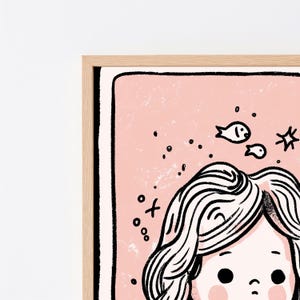 May include: A framed wall art print featuring a stylized illustration of a person with wavy hair against a soft pink background. The artwork includes black line drawings of small fish, bubbles, and a star, all enclosed within a light wood frame.