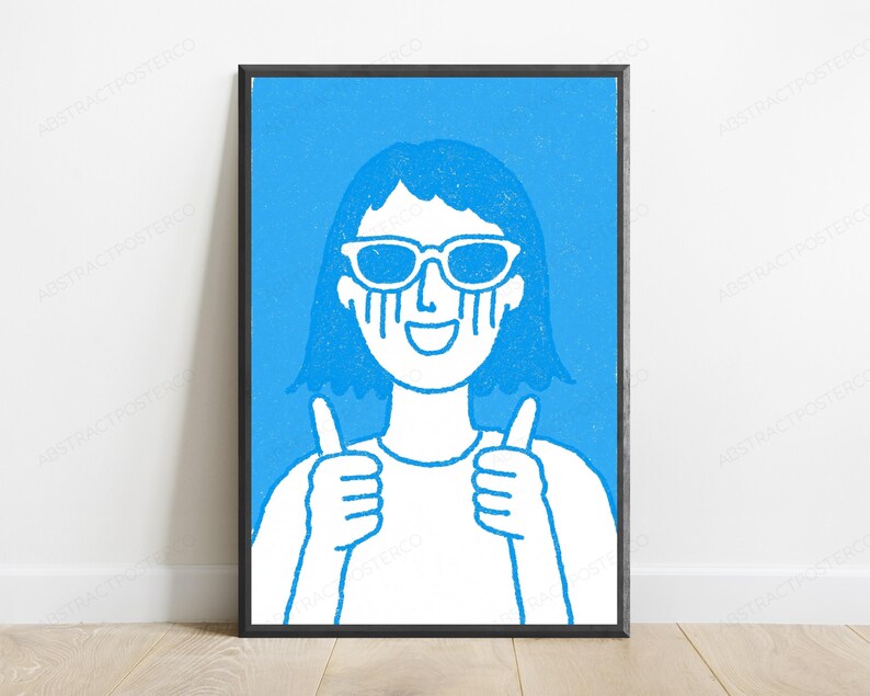 May include: A framed wall art print featuring a blue and white line drawing of a person with short hair wearing sunglasses, crying blue tears, smiling, and giving a double thumbs-up gesture. The illustration has a textured, hand-drawn aesthetic.