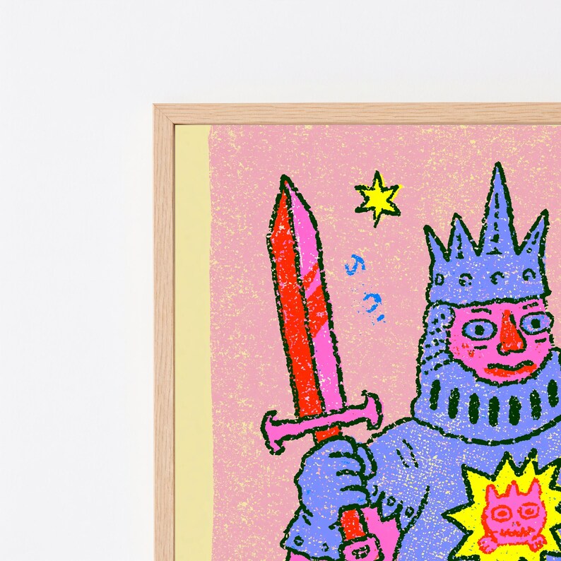 May include: A framed art print featuring a stylized illustration of a knight in blue armor holding a red sword. The knight wears a blue crown and has a pink face. A yellow star and a small yellow sun-like icon with a face are visible on the pink background.