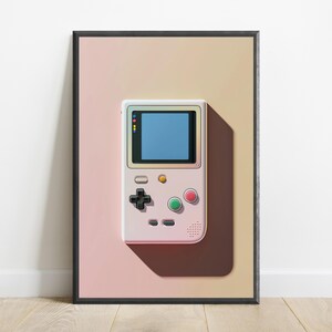 May include: A framed wall art print featuring a pale pink handheld gaming console with a blue screen, a black directional pad, and red and green circular buttons, set against a soft gradient background transitioning from light pink to beige.