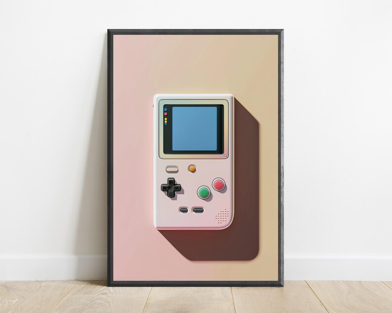 May include: A framed wall art print featuring a pale pink handheld gaming console with a blue screen, a black directional pad, and red and green circular buttons, set against a soft gradient background transitioning from light pink to beige.