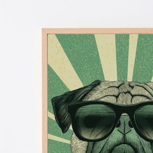 May include: A framed wall art print featuring a detailed illustration of a pug wearing black sunglasses. The background consists of a green and cream sunburst pattern with a distressed, textured effect. The frame is made of light-colored wood.