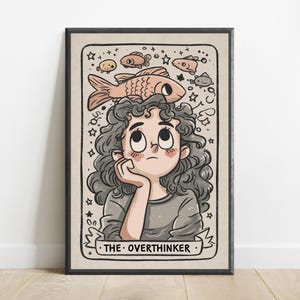 May include: A framed illustration featuring a person with curly dark hair looking upward at a large fish resting on their head. The scene includes smaller fish, stars, and swirls, with a banner at the bottom displaying the text THE OVERTHINKER.