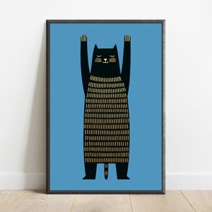 Op de afbeelding: Een ingelijste kunstprint met een zwarte kat met de voorpoten omhoog. De kat heeft gesloten ogen en een lichaam met verticale gouden lijnen tegen een effen blauwe achtergrond, geplaatst in een dunne zwarte lijst.