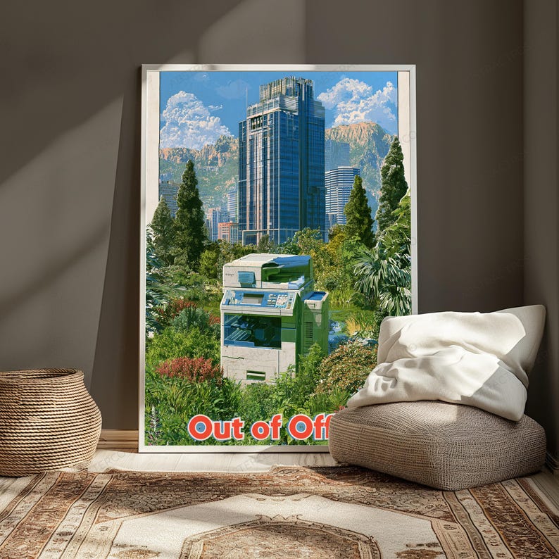 May include: A framed wall art print featuring a light-colored office photocopier situated in a lush green garden with trees and shrubs. In the background, a tall blue skyscraper rises against a blue sky with clouds. The text Out of Office is at the bottom.