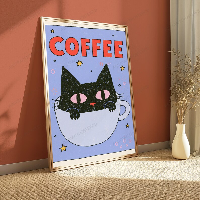 May include: A framed rectangular wall art print featuring a black cat with pink eyes peeking out of a white coffee mug against a light blue background. The word COFFEE is printed in large red letters at the top, surrounded by small yellow stars.
