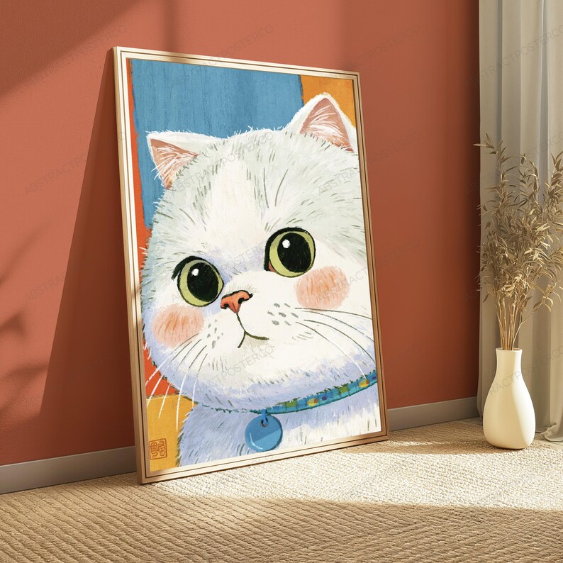 May include: A framed wall art print featuring a stylized illustration of a white cat with large green eyes and pink cheeks. The cat wears a blue collar with a round tag. The background consists of abstract blocks of blue, orange, and yellow colors.