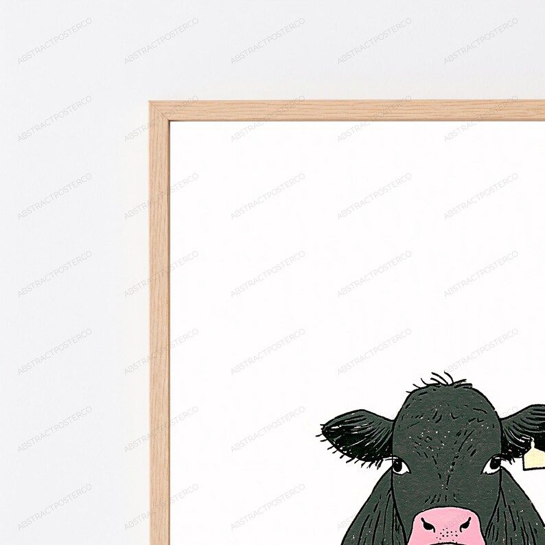 May include: A framed wall art print featuring a black cow illustration with a pink nose and a small yellow ear tag. The artwork is enclosed in a light-colored wooden frame, set against a plain white background with a repeating watermark pattern.
