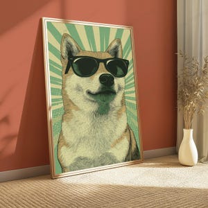 May include: A framed wall art print featuring a stylized illustration of a Shiba Inu dog wearing black sunglasses. The dog is centered against a light green background with radiating sunburst lines. The artwork has a light wood-toned frame.