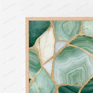 May include: A framed wall art piece featuring a mosaic pattern of green and white agate stone slices. The segments are separated by thin, textured gold lines that create a cracked, geode-like appearance within a light-colored wooden frame.
