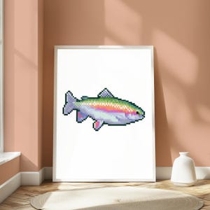 May include: A framed wall art print featuring a pixel art illustration of a rainbow trout. The fish is rendered in a digital style with a gradient of green, pink, and silver scales, a dark eye, and distinct fins, centered on a plain white background.
