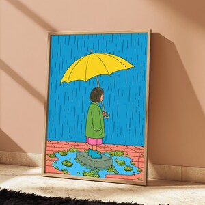 K&ouml;nnte beinhalten: Ein gerahmter Kunstdruck mit einer Cartoon-Illustration einer Person, die auf einem Steinblock in einer Pf&uuml;tze steht und einen gro&szlig;en gelben Regenschirm h&auml;lt. Die Person tr&auml;gt einen gr&uuml;nen Mantel, einen rosa Rock und blaue Stiefel vor blauem Regen.