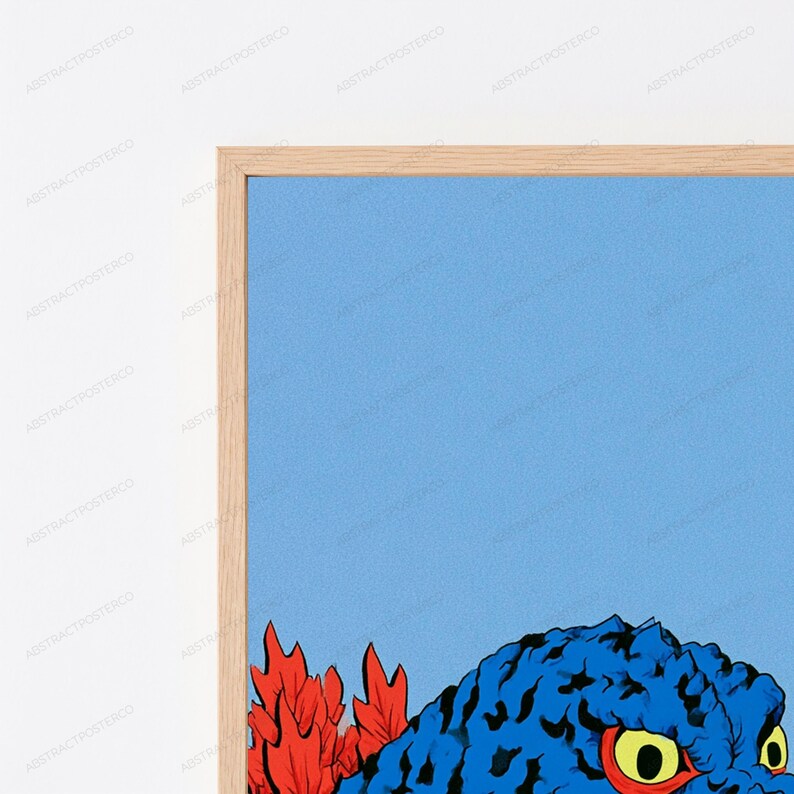 May include: A framed wall art print featuring a blue, textured creature with large yellow eyes and red pupils, positioned next to bright red, jagged, leaf-like shapes against a solid light blue background, enclosed in a light wood frame.