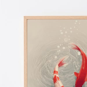 May include: A framed wall art print featuring two koi fish swimming in light gray water. One fish is solid orange-red, while the other is white with orange-red patches. Circular ripples and bubbles are visible on the water surface.