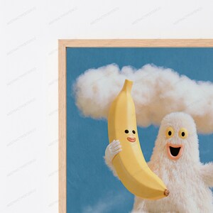 K&ouml;nnte beinhalten: Ein gerahmter Kunstdruck, der ein flauschiges wei&szlig;es Wesen mit weit ge&ouml;ffnetem Mund zeigt, das eine gelbe Banane mit l&auml;chelndem Gesicht h&auml;lt. Der Hintergrund ist ein blauer Himmel mit einer gro&szlig;en wei&szlig;en Wolke. Der Rahmen ist aus hellem Holz.