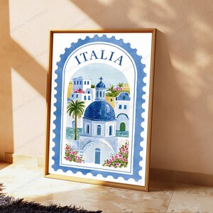 K&ouml;nnte beinhalten: Ein gerahmter Kunstdruck im Design einer Briefmarke mit dem Wort ITALIA am oberen Rand. Die Illustration zeigt ein Geb&auml;ude mit blauer Kuppel, wei&szlig;e Architektur, eine Palme und rosa Blumen im Aquarellstil mit einem blauen Rand.
