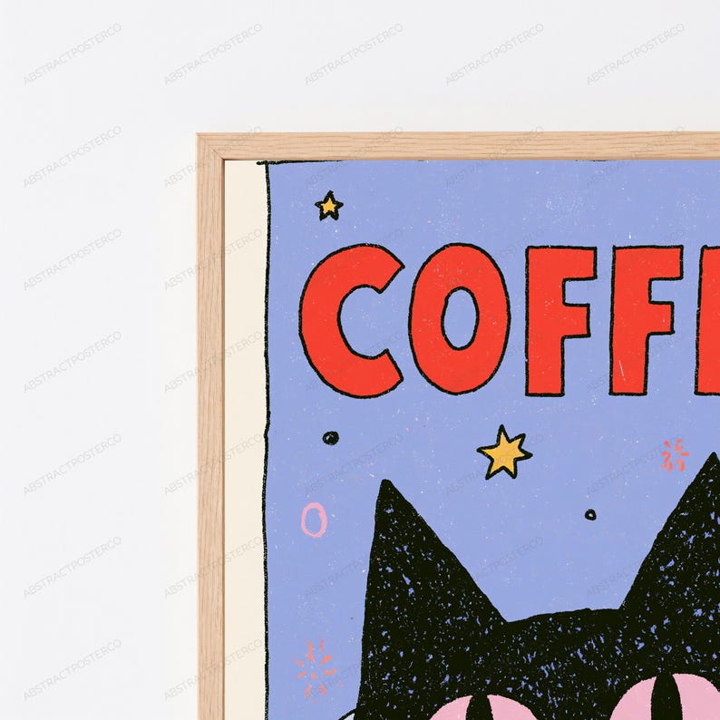 May include: A framed wall art print featuring a light blue background with the red text COFFEE at the top. A black cat illustration with large pink eyes is positioned below the text, surrounded by small yellow stars and various graphic symbols.