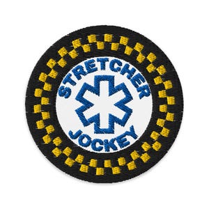 Op de afbeelding: Een geborduurde zwarte en gele patch met de tekst "Stretcher Jockey" en een blauwe medische ster in het midden.