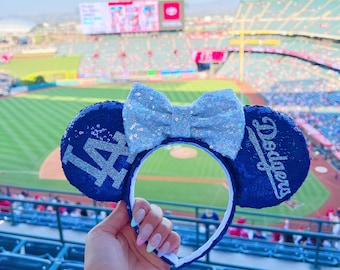 Puede incluir: Orejas de Minnie Mouse de béisbol azul y blanco con un lazo azul y el texto "Dodgers" y "LA" en blanco.