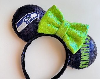May include: Black headband with a green bow and two sequined ears. One ear has a Seattle Seahawks logo and the other ear says "Seahawks".