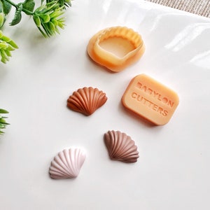 May include: Three different colored seashell shaped silicone molds, a larger seashell mold, and a rectangular silicone mold with the text "BABYLON CUTTERS" on it.