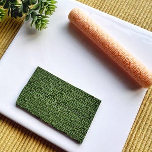 May include: Two rolling pins for baking, one is green and one is orange. Both have a Celtic knot design.