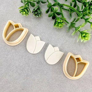 May include: Four cookie cutters in the shape of tulips. Two are made of metal and two are made of plastic.