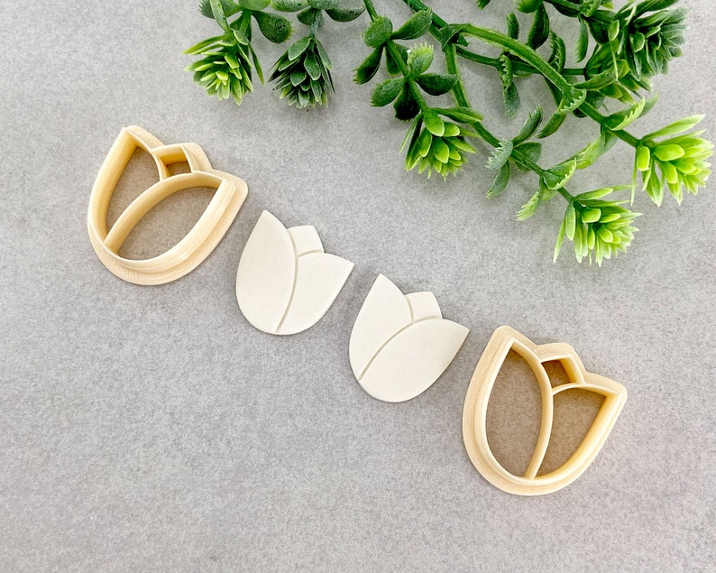 May include: Four cookie cutters in the shape of tulips. Two are made of metal and two are made of plastic.