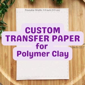 Op de afbeelding: Een rechthoekig vel transferpapier voor polymeerklei met een printbare breedte van 9,9 cm en een hoogte van 12,7 cm. Het papier heeft een gestippelde rand en paarse tekstoverlays met de tekst CUSTOM TRANSFER PAPER for Polymer Clay.