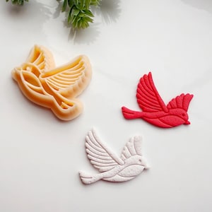 May include: Three cookie cutters shaped like birds. One is white, one is red, and one is beige.
