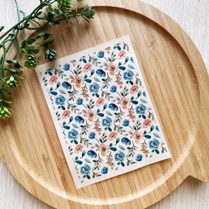 May include: A sheet of floral patterned paper with a white background and a repeating pattern of blue and peach flowers with green leaves.