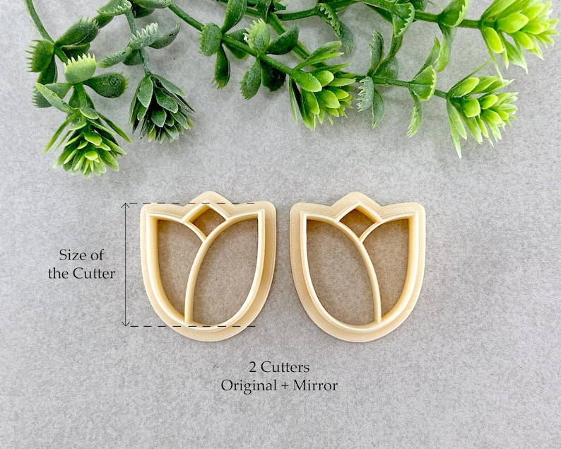 May include: Two plastic cookie cutters in the shape of a tulip. The cutters are beige and have a detailed design. The text "2 Cutters Original + Mirror" is printed below the cutters.