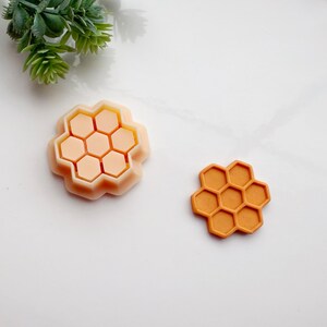 May include: Two honeycomb-shaped silicone moulds, one in a light peach colour and the other in a burnt orange colour.