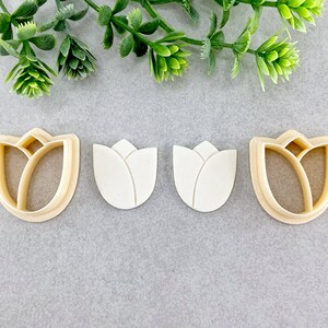 May include: Three cookie cutters shaped like a tulip flower. The cutters are made from a light brown plastic material.