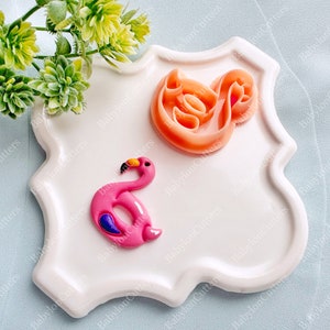 Op de afbeelding: Een wit keramiek bord met een roze flamingo en een werveling van oranje fondant. De flamingo houdt een roze opblaasbaar ring.