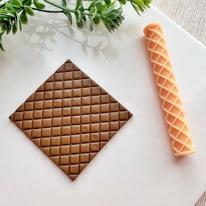May include: A brown square silicone mould with a waffle pattern and a light brown silicone roller with a waffle pattern.