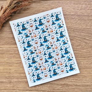 May include: A white sheet with a repeating pattern of blue witch hats, potion bottles, stars, and crescent moons. The hats have a blue brim and a dark blue pointed top. The potion bottles are orange and clear.