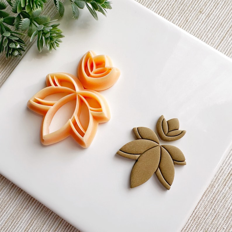 May include: Two cookie cutters, one in orange and one in brown, shaped like stylized flowers with five petals.