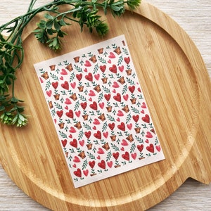 Peut inclure: Une feuille de papier blanc avec un motif répété de cœurs rouges dans des pots de fleurs avec des feuilles vertes. Les cœurs sont de différentes nuances de rouge et les pots sont bruns.
