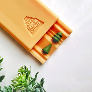May include: Orange silicone mold with the text "BABYLON cutters" and two green Christmas tree shapes.